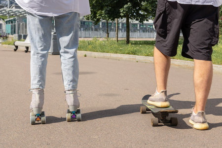 Young couple rollerblading and skateboarding in park. Happy and joyful girl and man doing sports...