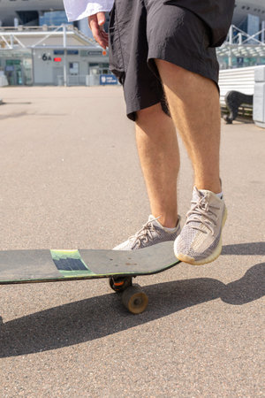 Young man in white shirt skateboarding in park. Vertical photo. High quality photoの写真素材