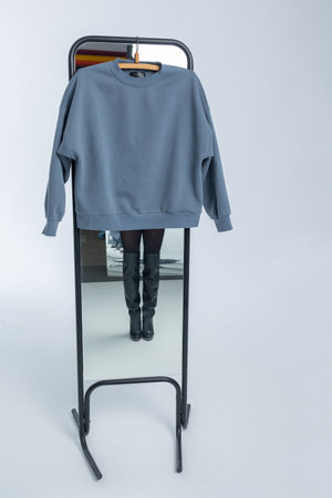 Grey sweatshirt hanging on light background. Vertical photo. High quality photoの写真素材