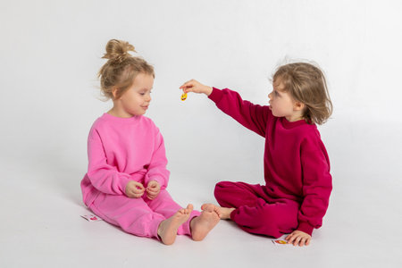 Two funny cute girls playing and having fun. Children with smiles and funny emotions on a light backgroundの写真素材