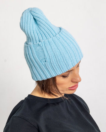 Portrait beautiful woman in blue hat. Pretty girl in warm clothes on grey background. Studio...
