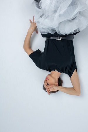 Model in black jumper, light grey skirt on white background. Vertical photo. High quality photoの写真素材