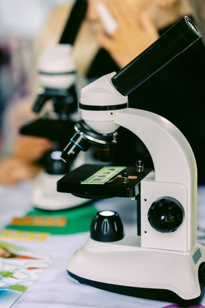 Modern white microscope on blurred background. Concept of teaching biochemistry to students and schoolchildren. Selective focus. Vertical photo. High quality photoの写真素材