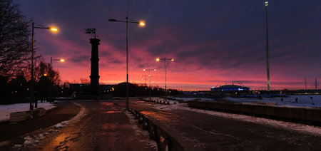 Panoramic view of winter landscape at fiery dawn. Silhouette of lighthouse and walking paths in park 300 anniversary of St. Petersburg, Russia.の写真素材