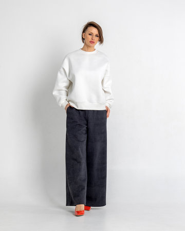 Portrait beautiful woman of model appearance. Girl in white sweatshirt, black trousers, red shoes on grey background. Pretty female with trendy makeup posing in studio. Vertical photo.の写真素材