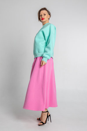 Beautiful girl of model appearance. Portrait of beautiful woman in mint color sweatshirt and pink skirt. Vertical photo. High quality photoの写真素材