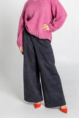Portrait beautiful woman of model appearance. Girl in pink jumper, black trousers, red shoes on grey background. Pretty female with trendy makeup posing in studio. Vertical photo.の写真素材
