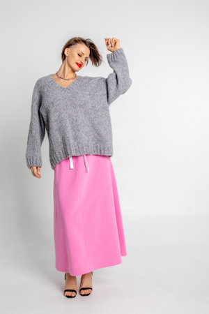 Beautiful girl of model appearance. Portrait of cheerful woman in gray jumper and pink skirt. Vertical photo. High quality photoの写真素材