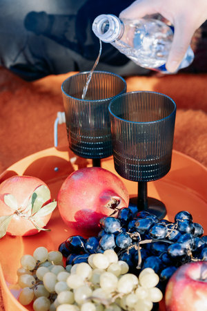 Autumn picnic on beach by sea. Fresh fruits, wine glasses, bottle, grapes, pomegranate near picnic basket on orange blanket. High quality photoの写真素材