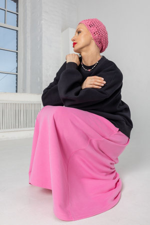 Portrait of woman in black jumper, pink skirt and beret on light background. Vertical photo. High quality photoの写真素材