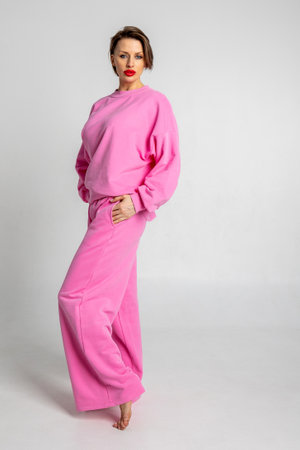 Portrait beautiful woman of model appearance. Girl in pink clothes on grey background. Studio photography. Pretty female with trendy makeup posing in studio. Vertical photo.の写真素材