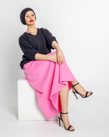 Beautiful woman in black jumper, pink skirt and black beret in French style. Bright makeup with red lipstick. Vertical photo. High quality photoの写真素材
