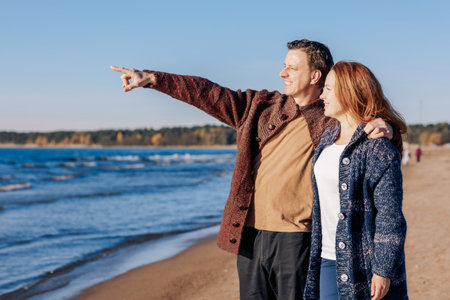Loving couple walks on beach along sea on sunny autumn day. Weekend and lifestyle concept. High quality photoの写真素材