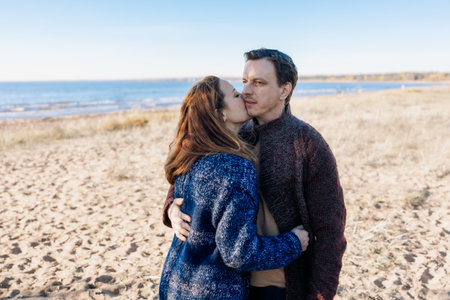 Loving couple walks on beach along sea on sunny autumn day. Weekend and lifestyle concept. High quality photoの写真素材