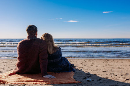 Loving couple walks on beach along sea on sunny autumn day. Weekend and lifestyle concept. Back view. High quality photoの写真素材
