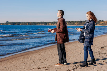 Loving couple walks on beach along sea on sunny autumn day. Weekend and lifestyle concept. High quality photoの写真素材