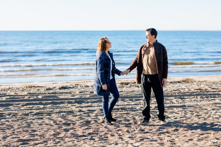 Loving couple walks on beach along sea on sunny autumn day. Weekend and lifestyle concept. High quality photoの写真素材