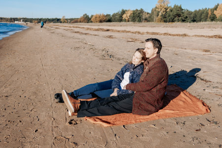 Portrait loving couple walks on beach along sea on sunny autumn day. Weekend and lifestyle concept. High quality photoの写真素材