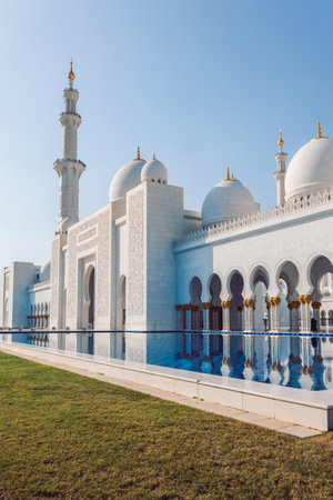 View of Sheikh Zayed Grand Mosque in Abu Dhabi made of white marble with flowers made of precious stones in design and beautiful reflections in water. Vertical photoの写真素材
