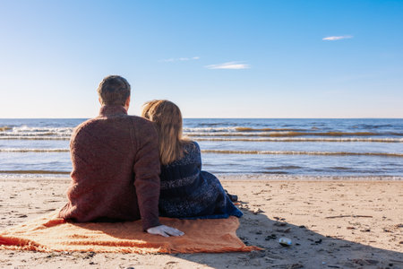 Loving couple walks on beach along sea on sunny autumn day. Weekend and lifestyle concept. Back view. High quality photoの写真素材