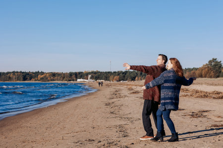 Young carefree couple in love throwing pebbles, shells, stones into sea outdoors. Fun game together. High quality photoの写真素材