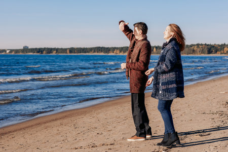 Loving couple walks on beach along sea on sunny autumn day. Weekend and lifestyle concept. High quality photoの写真素材
