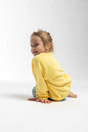 Portrait of beautiful cute little toddler girl. Child with funny face in yellow sweatshirt. Pretty smile kid in studio on white background. High quality photoの写真素材