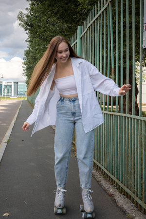 Beautiful girl with long hair rollerblading in park. Roller skating quads - popular and safe type of recreation. Vertical photo. High quality photoの写真素材
