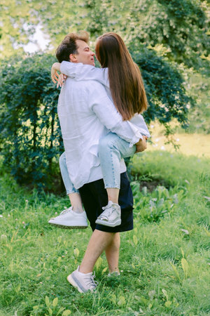 Loving couple of young girl and man are walking and having fun in park on warm summer day. Vertical photo. High quality photoの写真素材