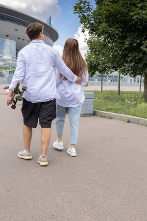 Young couple rollerblading and skateboarding in park. Happy and joyful girl and man doing sports together on warm summer day. Vertical photo. High quality photoの写真素材
