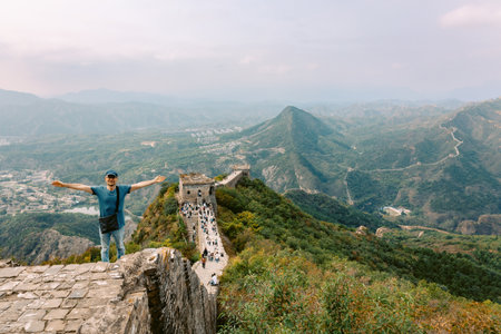 Man on Simatai section of Great Wall of China in its original, un-restored state. Watchtowers perched on mountain peaks, China, Beijing. High quality photoの写真素材
