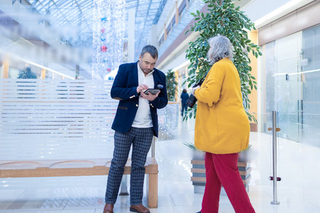 Female photographer shooting a businessman reading an ebook in a bright modern office. High quality photoの写真素材
