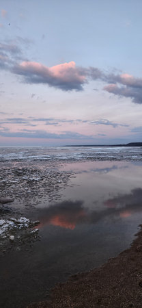 Spring landscape. Panoramic view of beautiful dawn on bay. Cumulus clouds over water in bright...