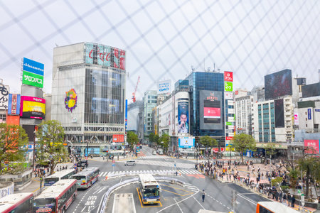 Tokyo, Japan - October 7, 2025: Metropolitan movement framing. Famous Shibuya intersection surrounded by advertising screens traffic and pedestrians Japan travel destination.のeditorial素材