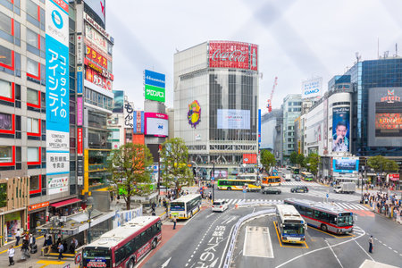 Tokyo, Japan - October 7, 2025: Metropolitan movement framing. Famous Shibuya intersection surrounded by advertising screens traffic and pedestrians Japan travel destination.のeditorial素材