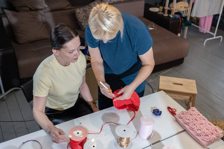 Three women crafting with colorful threads and crochet hooks at table in cozy workshop interior.