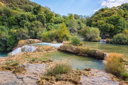 Nature daytime landscape - waterfall cascades surrounded by green forest, Krka National Park, Croatiaの写真素材