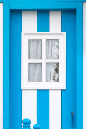 Fragment of a door with a window in typical small wooden house with colorful stripes in Costa Nova, Aveiro, Portugal. Detail of the house in famous resort Costa Nova.の写真素材