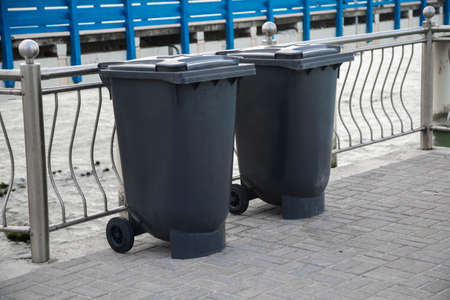 Closed and recycle receptacles trash bin outside. Black indoor waste containers for recycling on sidewalkの写真素材