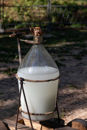 Large glass bottle with moonshine. Moonshine is strong alcoholic drink made at home. Concept of drunkennessの写真素材