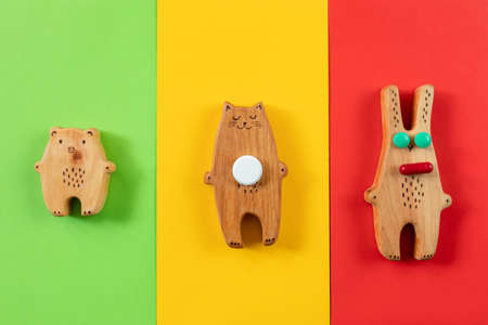 Wooden figurines of a bear, a hare and a cat with pills on colored backgrounds. The concept of...