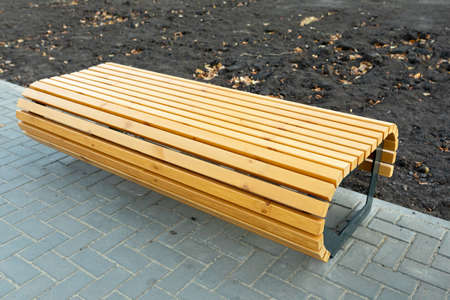 A modern comfortable wooden bench without a back in a new residential area. Landscaping of the house...