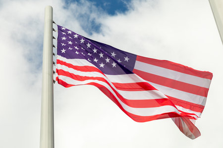 Large US Flag blowing in a strong wind on a cloudy sky. Close-up