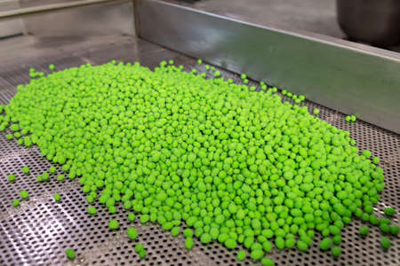 Green salted crunchy peanuts with wasabi in a metal mesh tray. Salted peanuts covered with colored...