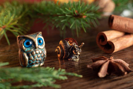 Christmas or New Year's composition with souvenir figures of owl and snail next to spruce twigs, cinnamon sticks and cardamom stars. Selective focusの写真素材