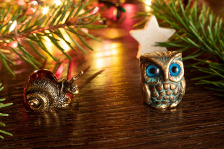 Christmas or New Year's composition with souvenir figures of owl and snail next to spruce twigs, cinnamon sticks and cardamom stars. Selective focus. Copy spaceの写真素材