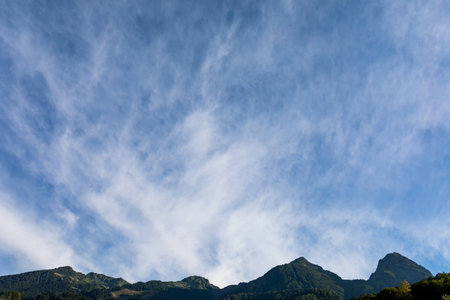 High blue sky with feathery clouds over the mountains at sunriseの写真素材