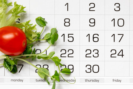 Micro green peas, lettuce leaf and tomato on the calendar grid. The concept of diet, weight lossor fastingの写真素材