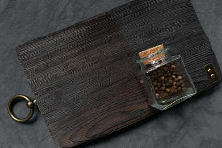 Vintage wooden decorative cutting board with metal decorative elements and bottle of spices on a...