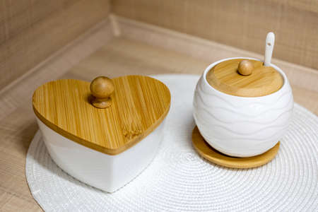 White ceramic sugar bowl and candy bowl with wooden lids on a kitchen table. selective focusの写真素材